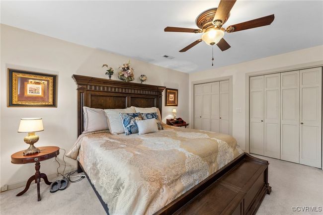 Bedroom featuring visible vents, light carpet, two closets, and a ceiling fan | Image 31