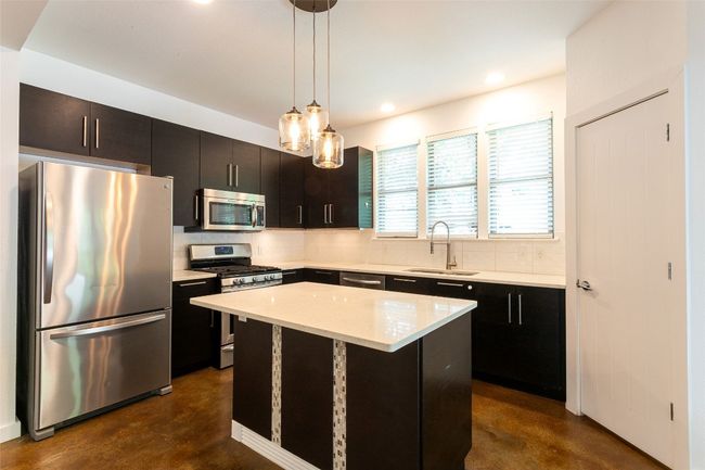 Kitchen with appliances with stainless steel finishes, concrete flooring, decorative backsplash, pendant lighting, and recessed lighting | Image 10