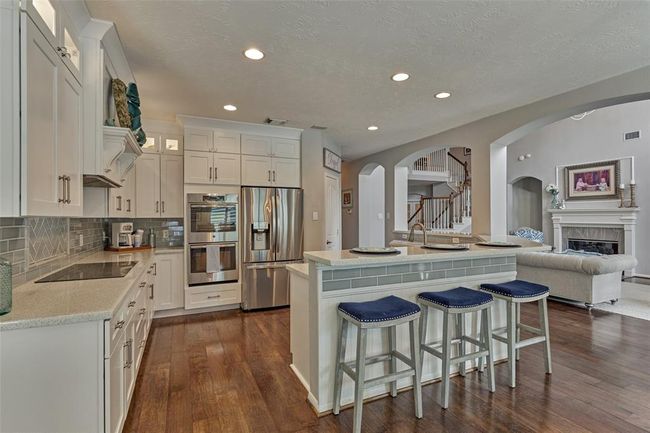 Kitchen is complete with double ovens and induction cooktop. Ample storage and tons of counter space. Also has eat-in bar area. | Image 19