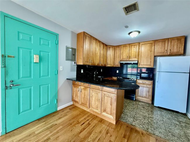 Kitchen with freestanding refrigerator, electric range oven, under cabinet range hood, a peninsula, and black microwave | Image 15