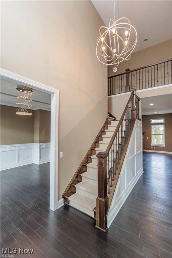 Stairs featuring a high ceiling, an inviting chandelier, wood finished floors, and baseboards | Image 16