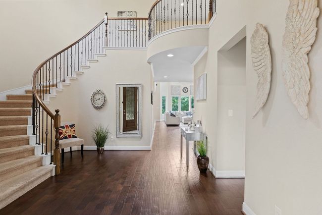Foyer entrance featuring stairs, baseboards, dark wood-style floors, and a high ceiling | Image 5