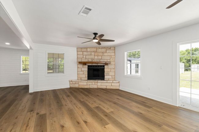 Spacious family room featuring elegant flooring, a cozy stone fireplace, and ample natural light from large windows. Perfect for gatherings and relaxation. | Image 24