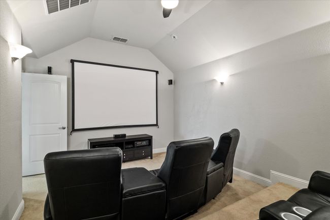 Home theater featuring ceiling fan, light colored carpet, and vaulted ceiling | Image 30