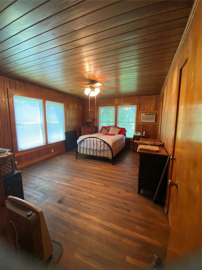 Bedroom with wood ceiling, hardwood / wood-style floors, wooden walls, a wall unit AC, and a ceiling fan | Image 20