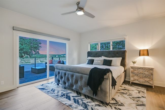 The primary bedroom features a sliding glass door that frames stunning lake views, creating a serene retreat | Image 11