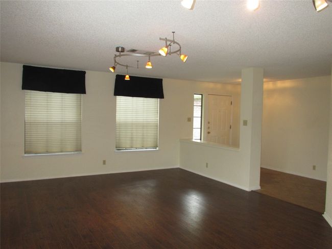 Unfurnished room featuring dark wood-style floors, a textured ceiling, and rail lighting | Image 9