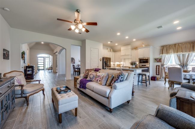 Living area featuring arched walkways, a ceiling fan, vaulted ceiling, light wood-style flooring, and recessed lighting | Image 10