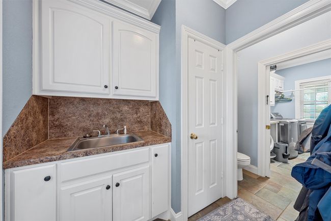 Bathroom featuring vanity, backsplash, toilet, independent washer and dryer, and stone finish flooring | Image 23