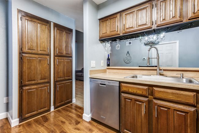 Kitchen featuring stainless steel dishwasher, light countertops, dark wood finished floors, and brown cabinetry | Image 20