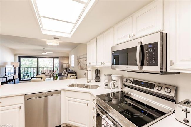 Kitchen featuring a sink, open floor plan, stainless steel appliances, a peninsula, and white cabinetry | Image 11