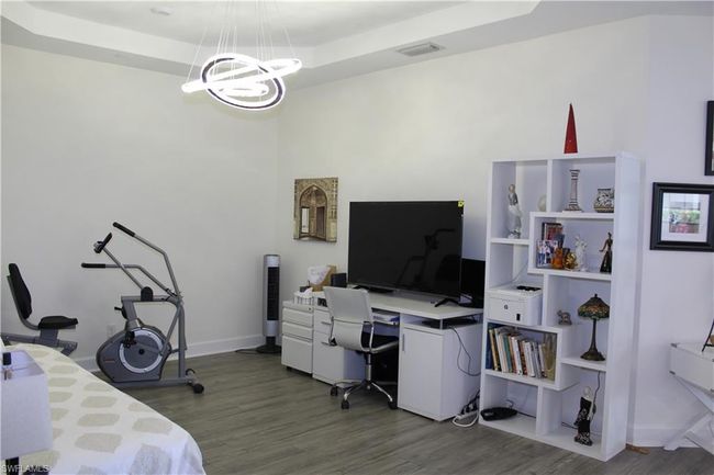 Open Den with baseboards, a notable chandelier, wood finished floors, and a raised ceiling | Image 13