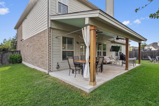 Rear view of house featuring brick siding, a patio area, a chimney, and ceiling fan | Image 34