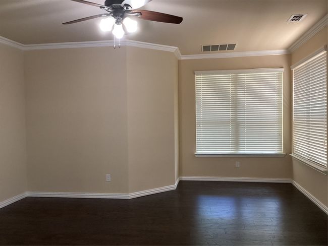 Spare room with a ceiling fan, dark wood-type flooring, baseboards, ornamental molding, and plenty of natural light | Image 11