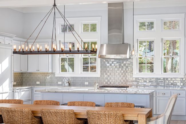 Kitchen featuring a healthy amount of sunlight, wall chimney exhaust hood, white cabinets, and tasteful backsplash | Image 13