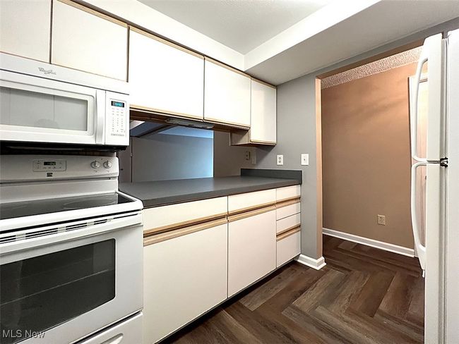 Kitchen featuring white appliances, white cabinetry, and dark countertops | Image 8