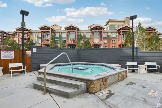 View of swimming pool featuring fence, a residential view, and a hot tub | Image 29
