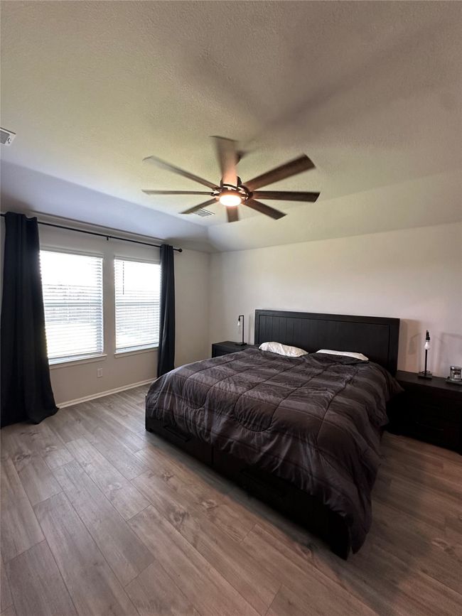 Bedroom with a ceiling fan, wood finished floors, a textured ceiling, baseboards, and visible vents | Image 20