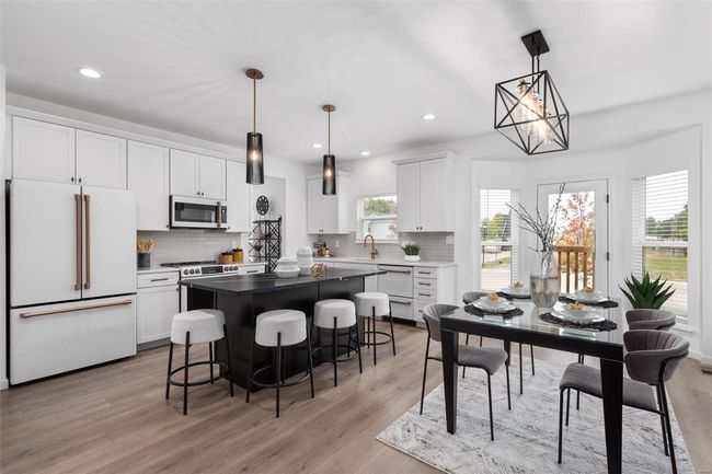 Kitchen featuring light wood-type flooring, decorative light fixtures, stainless steel appliances, and white cabinets | Image 27