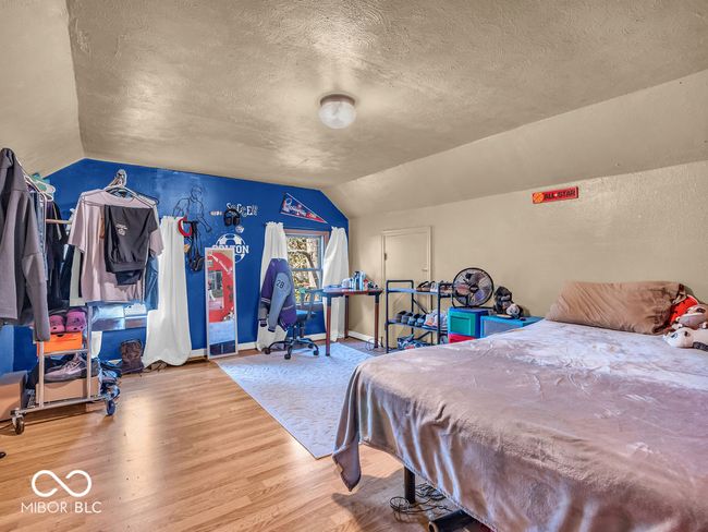 bedroom with lofted ceiling, a textured ceiling, wood finished floors, and baseboards | Image 17