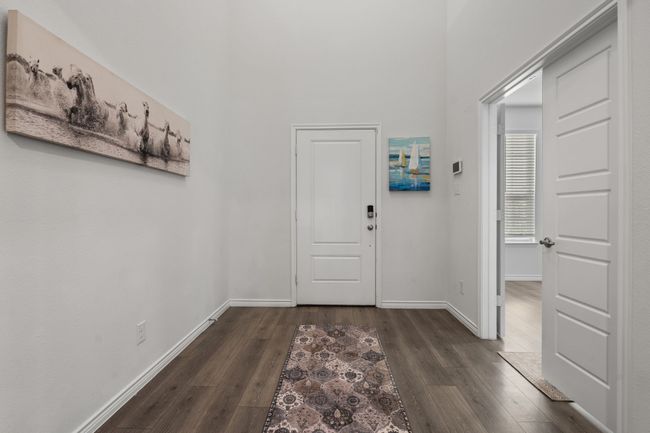 Foyer entrance featuring dark wood finished floors, baseboards, and a high ceiling | Image 6
