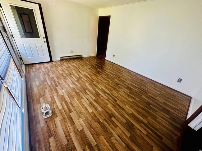 Empty room with a baseboard heating unit, wood finished floors, and baseboards | Image 5