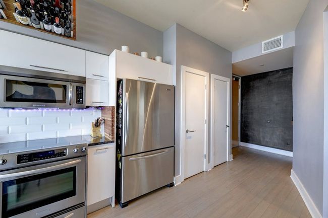 Kitchen featuring stainless steel appliances, white cabinetry, light wood-style flooring, baseboards, and backsplash | Image 4