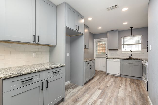 Kitchen with white appliances, a sink, light wood finished floors, decorative backsplash, and light stone counters | Image 16