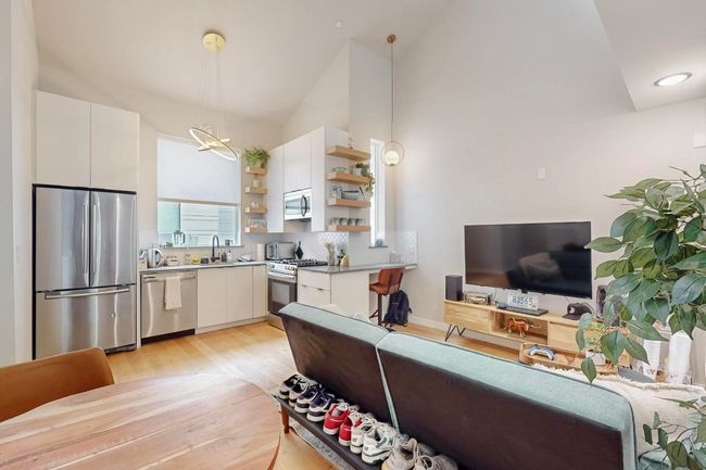 Kitchen featuring appliances with stainless steel finishes, open shelves, vaulted ceiling, light wood finished floors, and white cabinetry | Image 5