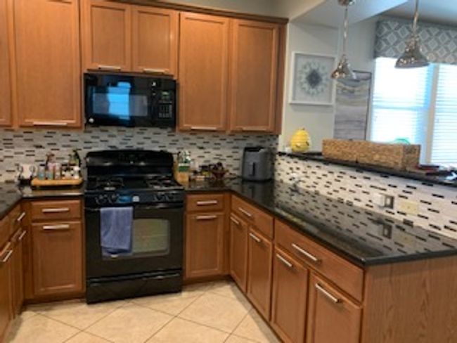 Kitchen featuring black appliances, a peninsula, and decorative backsplash | Image 7