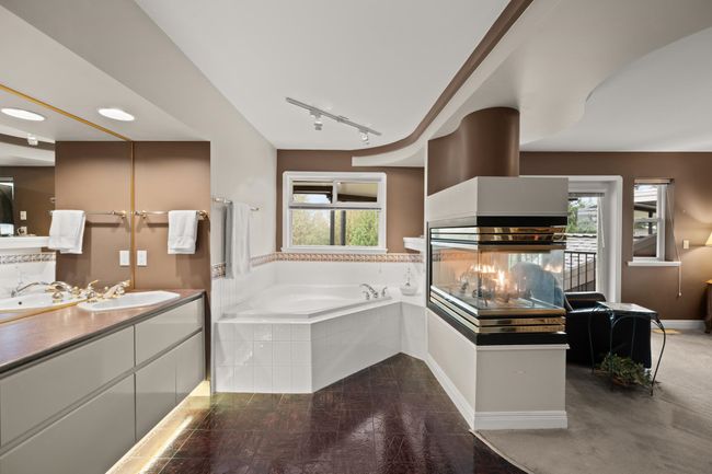 Full bath with a multi sided fireplace, plenty of natural light, vanity, and a garden tub | Image 26