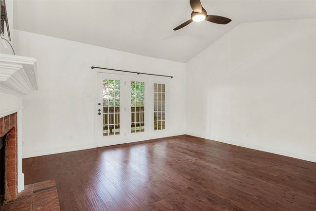 Unfurnished living room featuring a fireplace, lofted ceiling, ceiling fan, and dark wood finished floors | Image 8