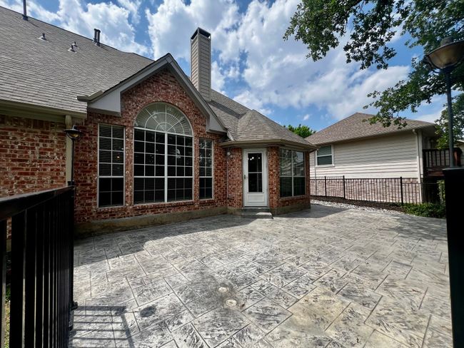 Rear view of property featuring brick siding, fence, a chimney, and a patio area | Image 28