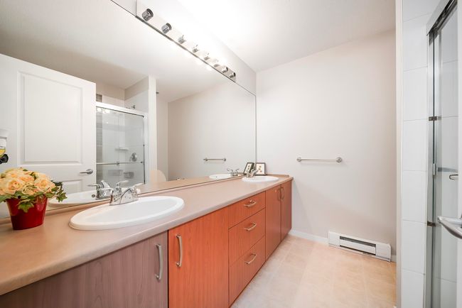 Full bathroom featuring a sink, a baseboard radiator, double vanity, and a shower with shower door | Image 27