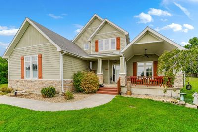 Craftsman-style house featuring a porch, ceiling fan, and a front lawn | Image 1