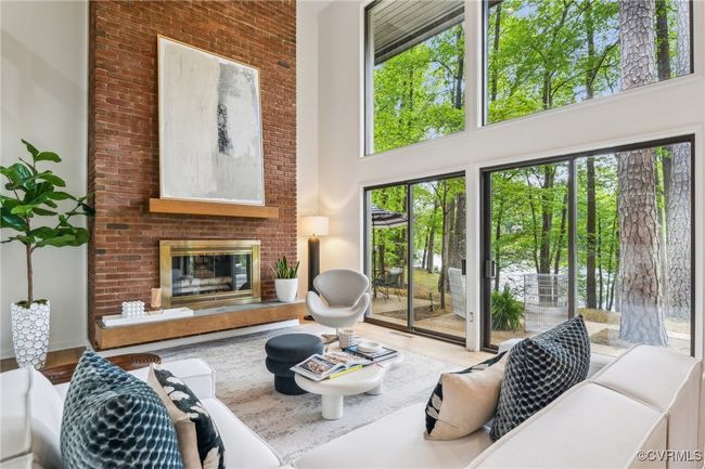Living room featuring wood finished floors, a towering ceiling, and a fireplace | Image 17