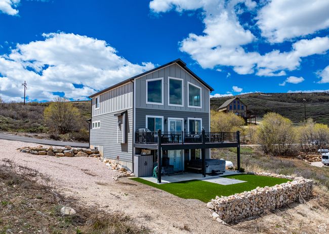 Back of property featuring a hot tub, board and batten siding, a patio area, and a deck | Image 5