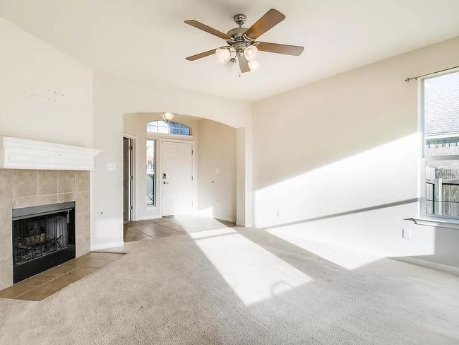 Unfurnished living room with carpet, a fireplace, a ceiling fan, and baseboards | Image 6