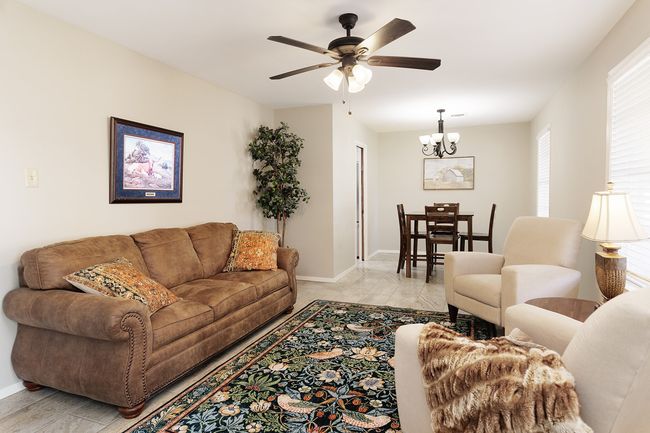 Living room with baseboards and ceiling fan with notable chandelier | Image 4