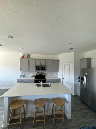 Kitchen featuring dark hardwood / wood-style flooring, refrigerator, gray cabinetry, and a large island | Image 3