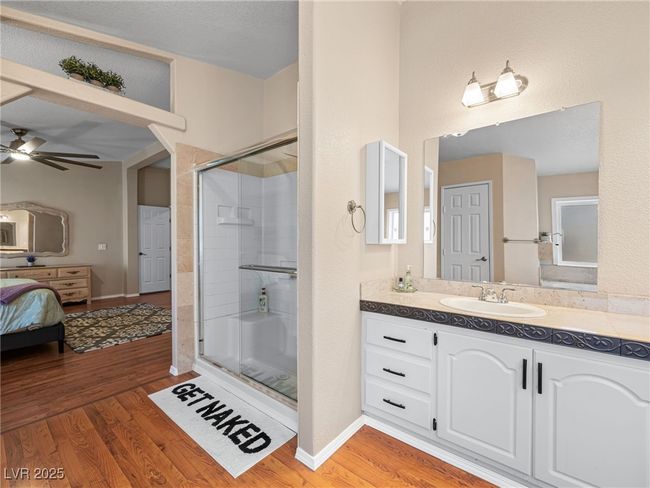 Ensuite bathroom with connected bathroom, a stall shower, wood finished floors, vanity, and a ceiling fan | Image 36