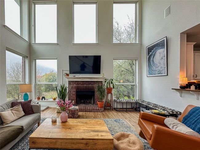 Living room featuring a towering ceiling, a brick fireplace, healthy amount of natural light, and wood finished floors | Image 8