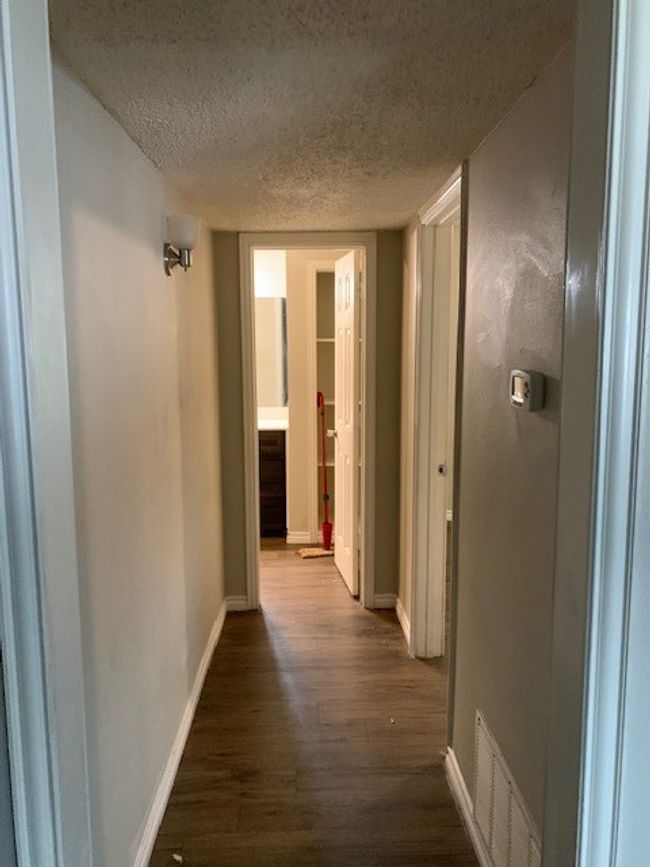 Hall featuring dark wood finished floors, a textured ceiling, and baseboards | Image 10