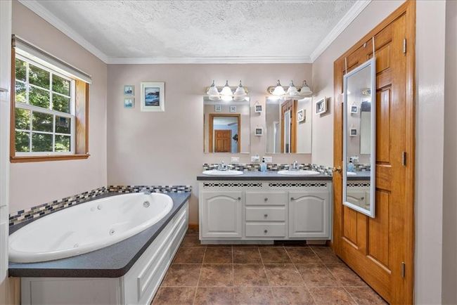 Bathroom featuring a sink, a whirlpool tub, crown molding, and a textured ceiling | Image 20