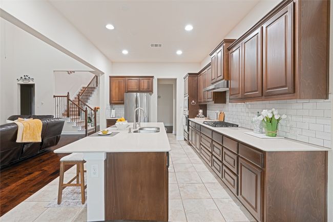 Kitchen with under cabinet range hood, a kitchen bar, backsplash, open floor plan, and recessed lighting | Image 15