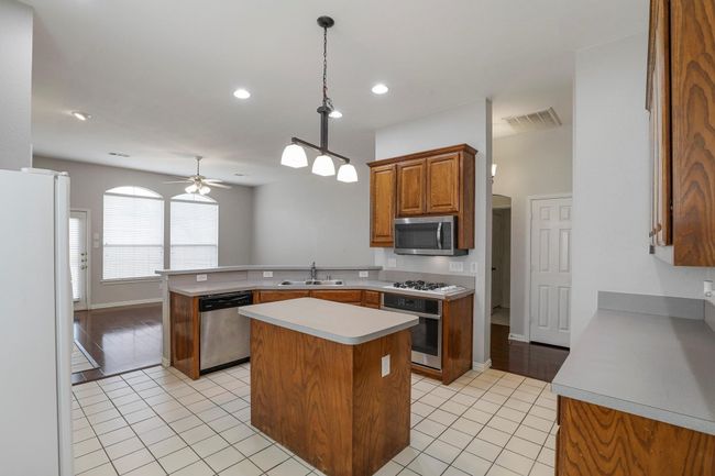 Kitchen featuring stainless steel appliances, a peninsula, a ceiling fan, light countertops, and light tile patterned floors | Image 6