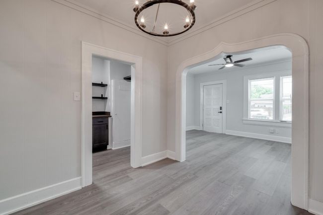Spare room featuring arched walkways, a chandelier, crown molding, wood finished floors, and a ceiling fan | Image 29