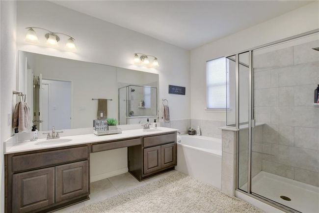 Bathroom with a stall shower, tile patterned floors, a bath, and double vanity | Image 20