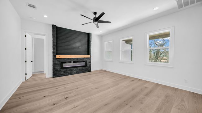 Unfurnished living room with visible vents, a large fireplace, baseboards, and light wood finished floors | Image 7