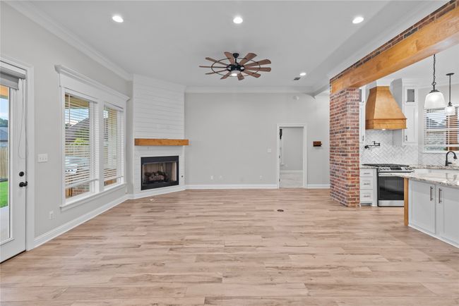 Unfurnished living room with ornamental molding, light wood-style flooring, recessed lighting, a ceiling fan, and a large fireplace | Image 6